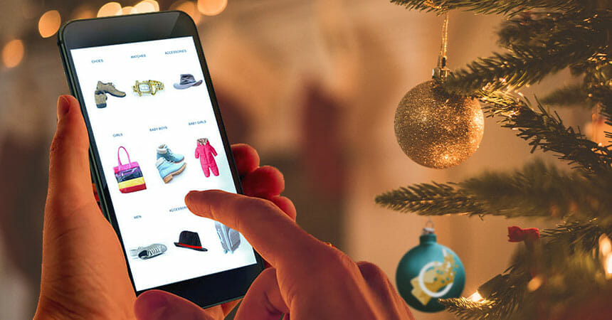 person using smartphone to shop for gifts online next to a christmas tree