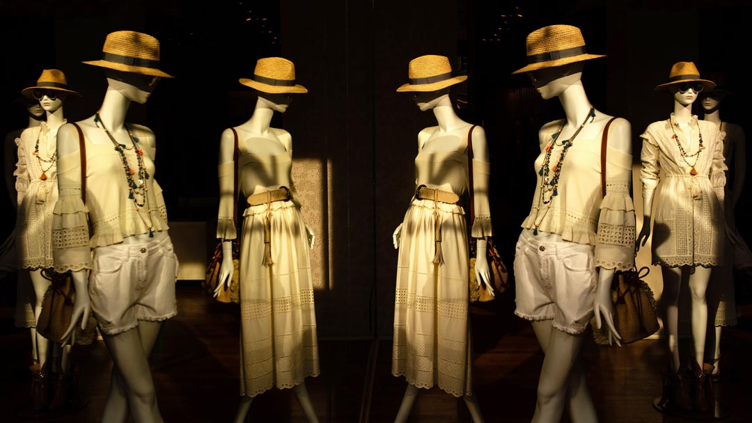 a crowd of mannequins dressed in white wearing straw hats