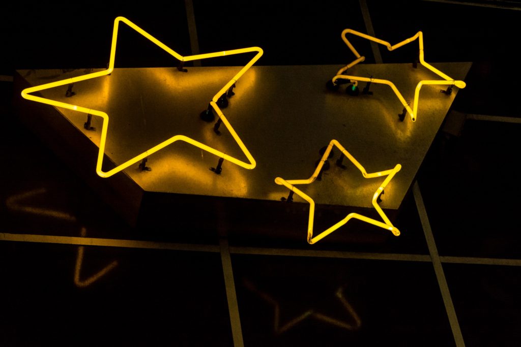 three five-pointed stars made from golden-yellow neon