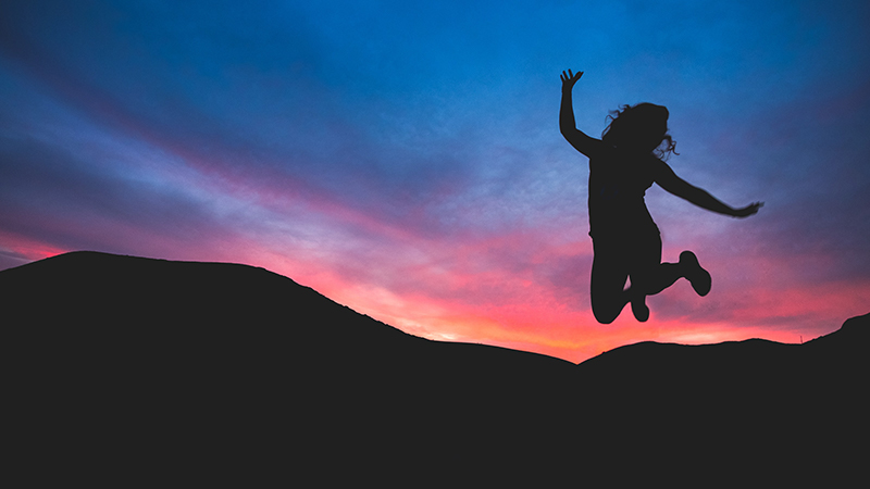 Girl jumping in front of sunset
